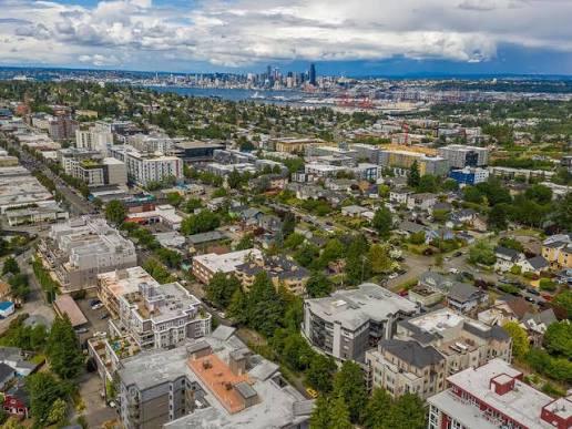 Aerial view of a residential neighborhood in Seattle, with West Seattle Link Extension relocation benefits highlighted by the city skyline and waterfront in the distance.