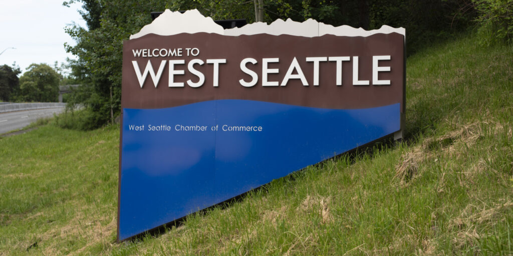 Welcome to West Seattle sign on a grassy hillside near the light rail business relocation help area.